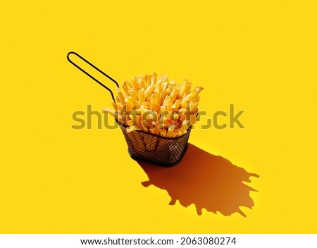 French fries in fryer basket on yellow pastel background