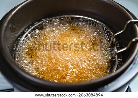 top view. oil boiling in a deep fryer. in the basket of the fryer cook shrimp in batter or potatoes. gadgets for the kitchen. cooking seafood in boiling vegetable oil. Royalty-Free Stock Photo #2063084894