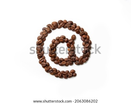 Symbol at made from roasted coffee beans on white isolated background. At sign. White and brown. Decoration, design. Macro, close-up.