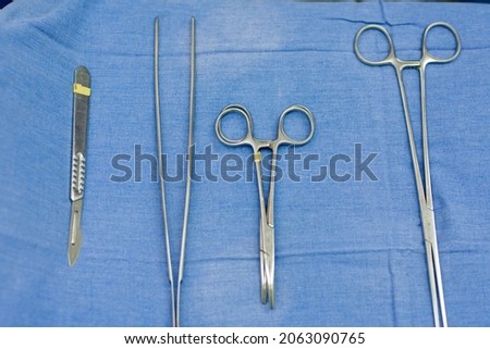 two pairs of scissors and tweezers on a blue background, close-up