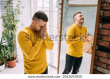 A man with bipolar disorder at the mirror. Bipolar affective disorder. A person with manic-depressive psychosis. Mental illness. A person with depression. A man is reflected in the mirror Royalty-Free Stock Photo #2063092850