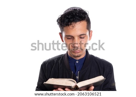 Latin man practicing Judaism isolated on white background. Young man with kippah reading bible. Royalty-Free Stock Photo #2063106521