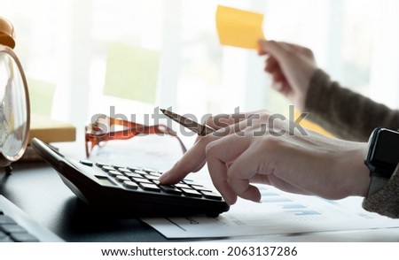 Close up accountant working on desk using calculator for calculate finance report in office
