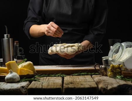 Ingredients for making pizza, pie, focaccia on a wooden table. The chef is holding the prepared dough in his hands. Restaurant, hotel, cafe, home cuisine. Step-by-step recipe, cooking blog.