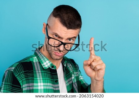 Photo of young unhappy man point finger warning rule bad mood wear glasses isolated on blue color background