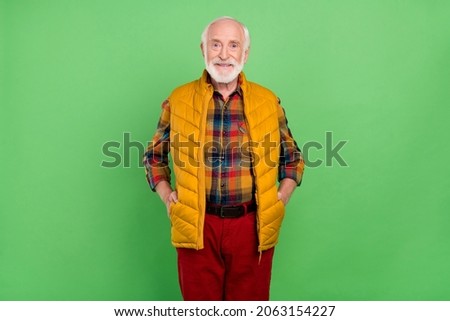 Photo of pretty charming senior gentleman wear yellow vest walking smiling isolated green color background