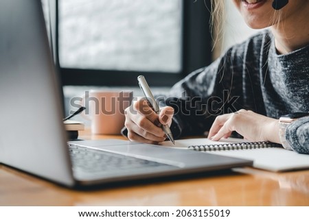 Close up photo of woman writing making list taking notes in notepad working or learning on laptop indoors- educational course or training, seminar, education online concept