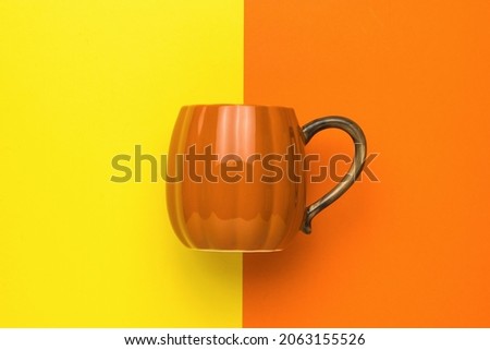 Orange pumpkin-style mug on a yellow and orange background. Pumpkin style.