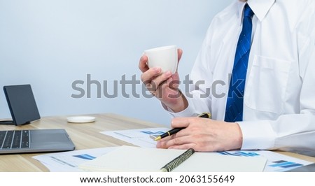 executive hold hot coffee cup while breaking from working with white copy space background for making meeting presentation, professional businessman busy work on the business data graph