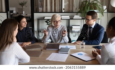 Lady boss. Elderly female ceo leader of business team coordinate work of multiethnic staff on meeting at boardroom. Elegant senior woman director of department speak on briefing set tasks to employees Royalty-Free Stock Photo #2063155889