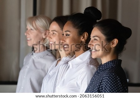 Business group of four professional confident diverse age multicultural female partners executives teammates stand in oblique line look forward with smile. Focus on millennial asian businesswoman face Royalty-Free Stock Photo #2063156051