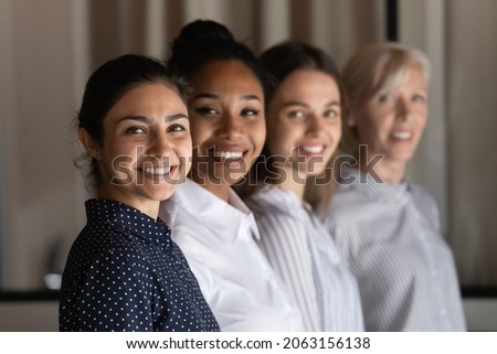 Multi ethnic group of successful confident women office workers professional experts stand in row one after another look at camera. Selective focus on young indian female team leader headshot portrait Royalty-Free Stock Photo #2063156138