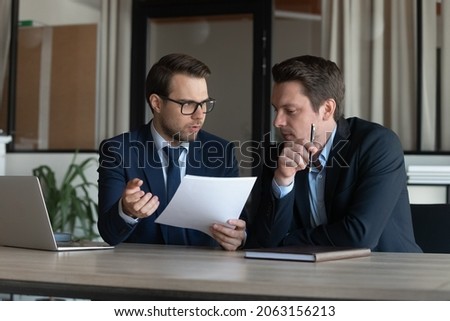 Serious young man supervisor analyse financial report of responsible worker pay attention on mistakes propose correction. Professional insurance agent discuss paper policy terms conditions with client Royalty-Free Stock Photo #2063156213