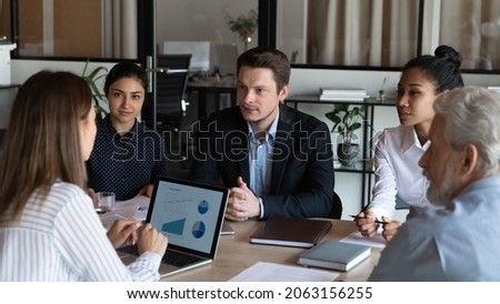 Negotiations. Diverse business partners sit at conference table talk speak develop work strategy discuss stats information. Multiracial corporate employees meet at briefing share ideas set job targets Royalty-Free Stock Photo #2063156255