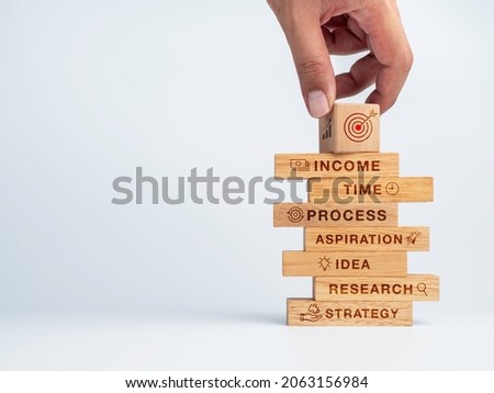 6 options or steps for business concept. Hand put the goal target icon on wood cube on the top of stack of wooden blocks with words of key to success and icons on white background with copy space.