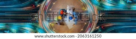 Top view of architectural engineer working on his blueprints with documents on construction site. meeting, discussing,designing, planing. Road traffic an important infrastructure Royalty-Free Stock Photo #2063161250