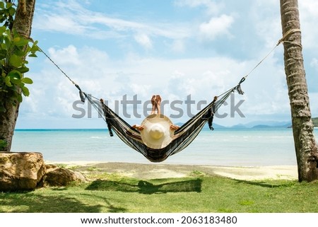 Summer vacations concept. Happy woman in black bikini relaxing in hammock on tropical beach Royalty-Free Stock Photo #2063183480