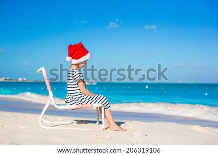 Little adorable girl wearing Santa hat at tropical beach