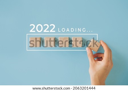 Female hand putting wooden cube for countdown to 2022. Loading year from 2021 to 2022. New year start concept Royalty-Free Stock Photo #2063201444