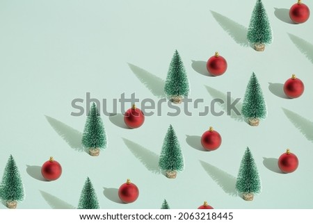 Arranged green New Year and Christmas tree with red bauble on a mint pastel background. Pattern. Copy space.