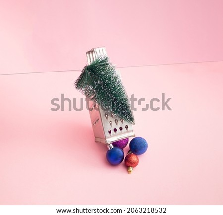 Metal silver grater on which there is a Christmas tree from which New Year's colorful baubles decorations fall out. Minimalni New Year and concept.
