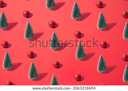Arranged green New Year and Christmas tree with red bauble on a red pastel background. Pattern.