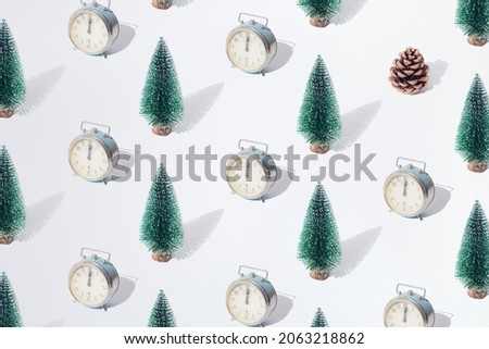 Arranged green New Year and Christmas tree with old silver retro watch with hand on twelve midnight hour and brown cone on a white pastel background. Pattern.