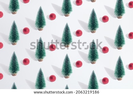 Arranged green New Year and Christmas tree with red bauble on a white pastel background. Pattern.