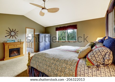 Spacious bedroom with vaulted ceiling. View of rustic fireplace and wardrobe.