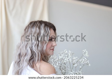 young beautiful blonde girl posing in a photo studio with a bouquet of flowers