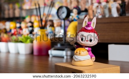 Cute monster figure on brown desk with figures background