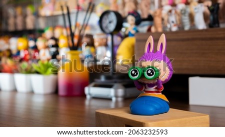 Cute monster figure on brown desk with figures background