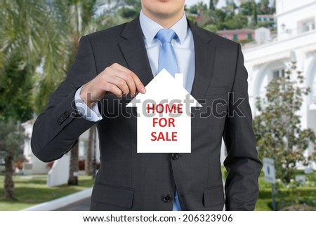 A property agent holding the banner - Home for Sale, real estate sign.