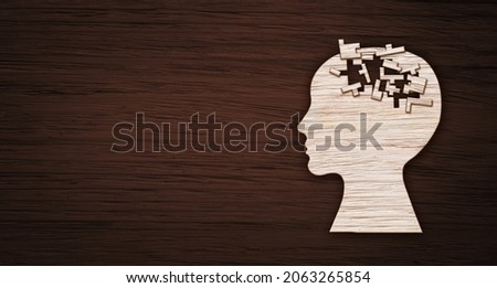 Mental health symbol. Human head silhouette with a puzzle cut out from wooden background.
