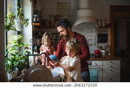 Mature father with two small children washing dishes indoors at home, daily chores concept. Royalty-Free Stock Photo #2063272550