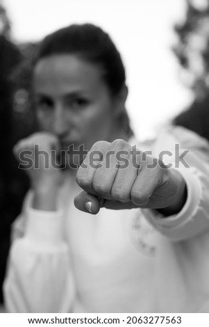 black and white portrait of woman punching towards camera