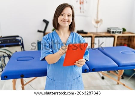 Brunette woman with down syndrome working using tablet at physiotherapy clinic Royalty-Free Stock Photo #2063287343