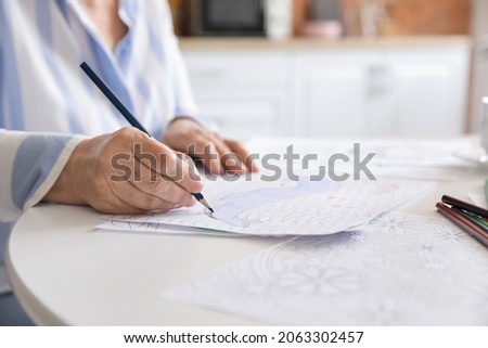 Senior woman coloring picture at table, closeup