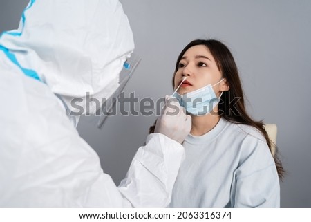 doctor with PPE suit test coronavirus(covid-19) to young woman by nasal swab 