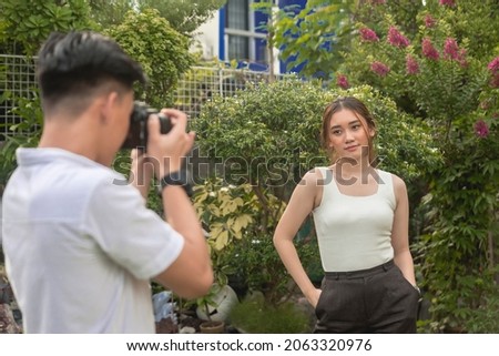 A hobbyist photographer takes a picture of his girlfriend with a DSLR. A model posing for her social media photos.