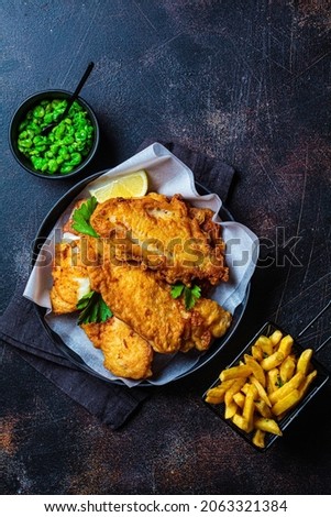 Fish and chips with green peas on a dark background, top view. British cuisine concept.