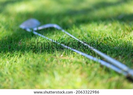 Detail of Golf clubs  on green, selective focus, light and shadows. Background for golf, sport, resort, vacation.