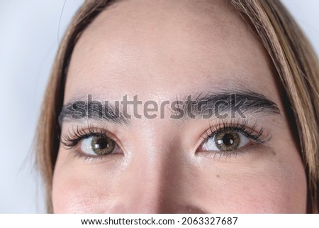 Closeup of the forehead and eyes of a Filipina woman in her 20s. With eyelash extensions and amber contact lenses.