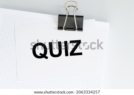 Quiz text on a card that is attached to white paper on a light background on a clip