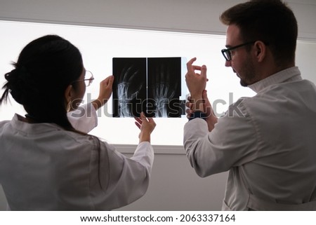 Professional medical team examining hand x-ray image. Rheumatoid arthritis. Royalty-Free Stock Photo #2063337164
