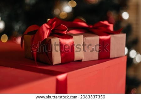 The concept of Christmas and New Year 2021. A festive greeting card with unfocused festive lights in the background. Christmas gifts with a red bow.