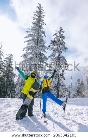 couple having fun at ski resort man with snowboard woman with ski