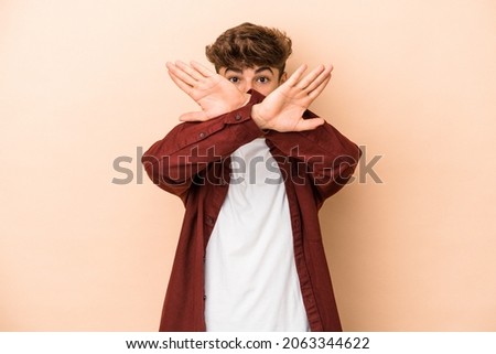 Young arab man isolated on beige background doing a denial gesture