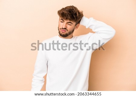 Young arab man isolated on beige background tired and very sleepy keeping hand on head.