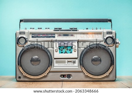 Retro outdated portable cassette tape recorder from 80s on wooden table front mint blue wall background. Vintage old style filtered photo Royalty-Free Stock Photo #2063348666